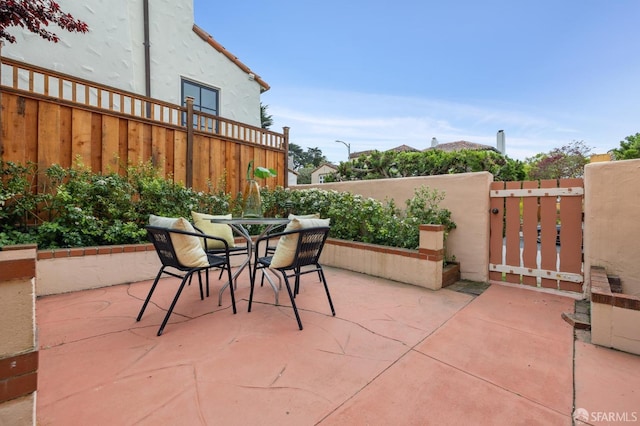 view of patio featuring fence, outdoor dining area, and a gate