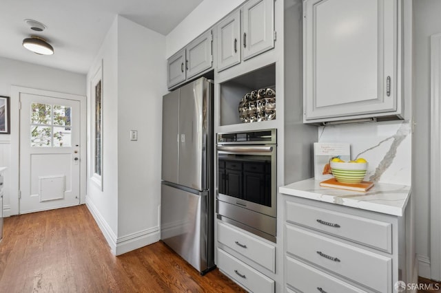 kitchen featuring baseboards, dark wood-style flooring, light stone countertops, gray cabinets, and stainless steel appliances