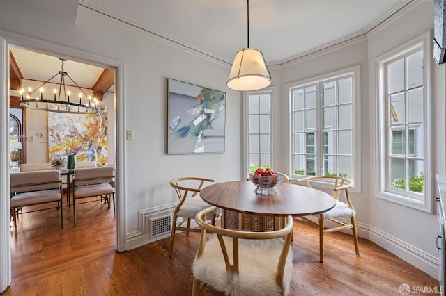 dining space featuring ornamental molding, baseboards, an inviting chandelier, and wood finished floors