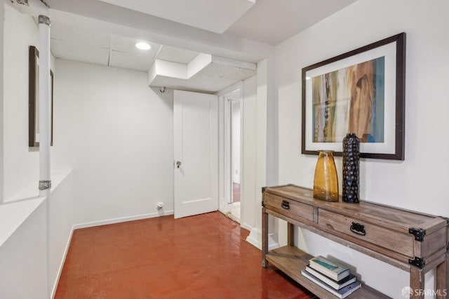 interior space with finished concrete flooring, a paneled ceiling, baseboards, and recessed lighting