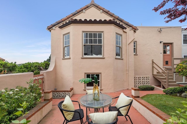 back of property with a patio area, outdoor dining space, and stucco siding