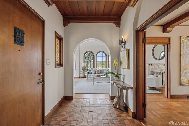 entryway featuring arched walkways, baseboards, and wood ceiling