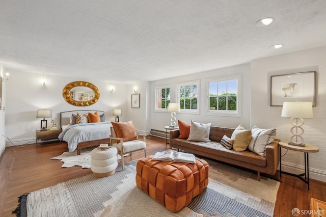 bedroom featuring baseboards, wood finished floors, and a textured ceiling