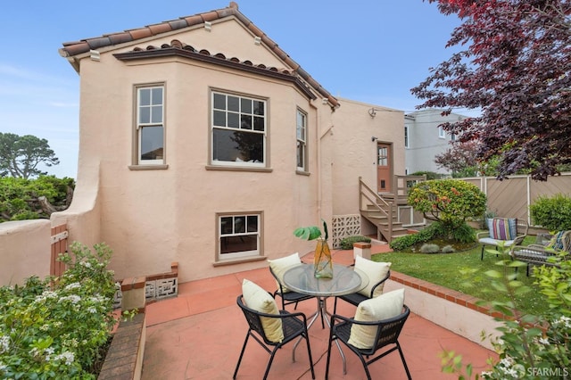 back of house with a patio area, outdoor dining space, fence, and stucco siding