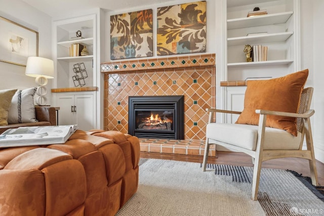 living area featuring wood finished floors, a fireplace, and built in shelves