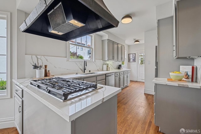 kitchen featuring gray cabinets, gas cooktop, under cabinet range hood, dishwasher, and a sink