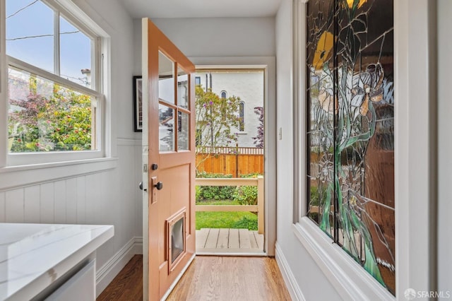 doorway to outside featuring a wealth of natural light, wainscoting, and wood finished floors