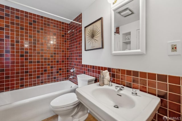 full bath featuring toilet, a sink, washtub / shower combination, and tile walls