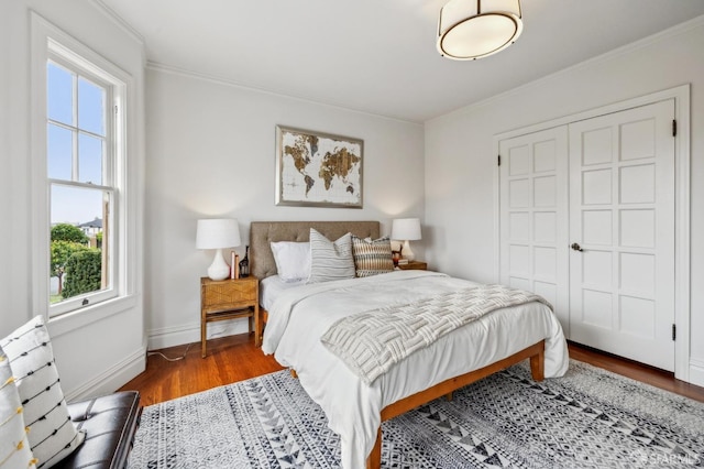 bedroom featuring crown molding, wood finished floors, a closet, and baseboards