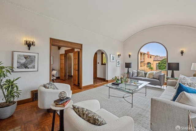 living area with arched walkways, visible vents, baseboards, and vaulted ceiling