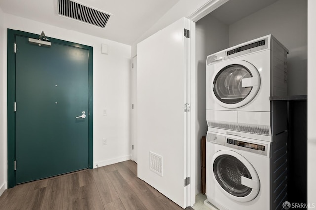 clothes washing area with stacked washer and clothes dryer and hardwood / wood-style flooring