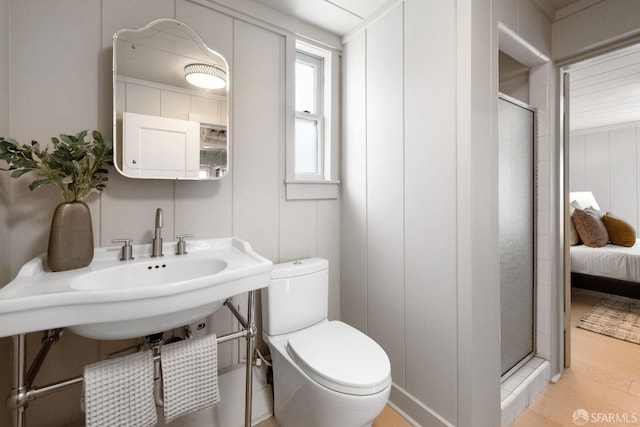 bathroom featuring a shower with door, wood-type flooring, and toilet