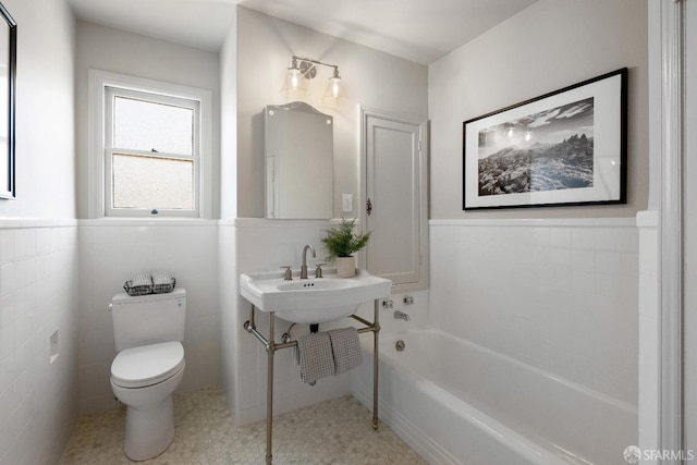 bathroom featuring toilet, tile walls, a tub, and sink