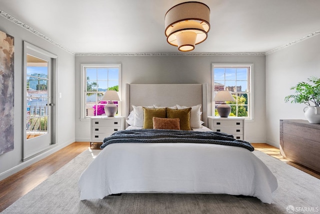 bedroom featuring hardwood / wood-style floors, multiple windows, and crown molding