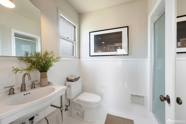 bathroom with tile patterned flooring, toilet, tile walls, and sink