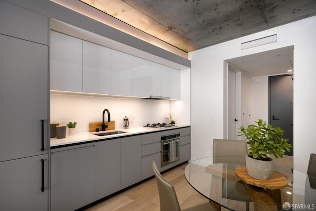 kitchen with light hardwood / wood-style flooring, gray cabinetry, appliances with stainless steel finishes, and sink