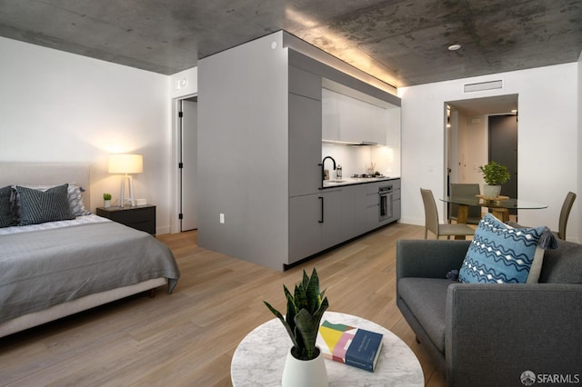 bedroom with sink and light hardwood / wood-style floors