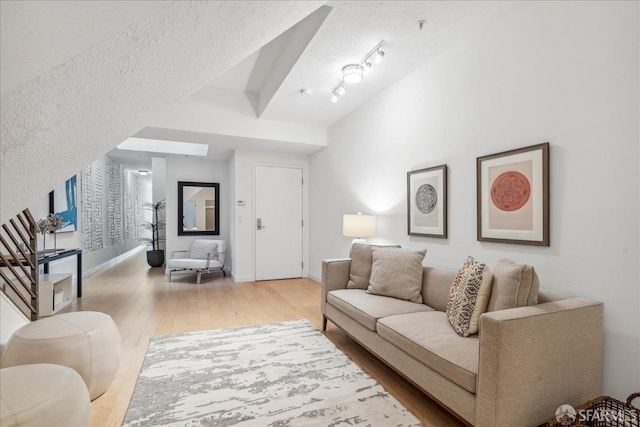 living area featuring a textured ceiling, baseboards, and wood-type flooring