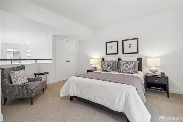 bedroom with light colored carpet, baseboards, and a closet