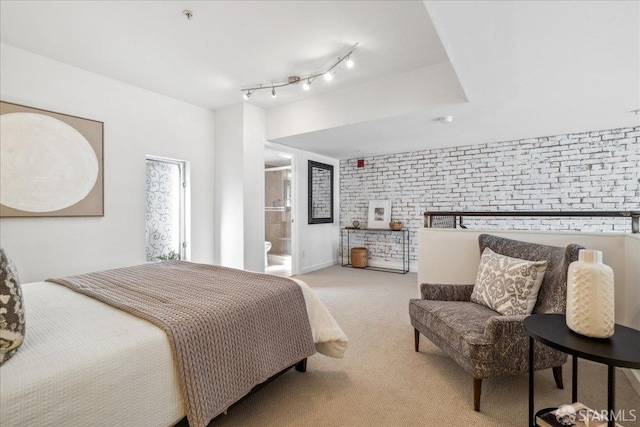 carpeted bedroom with ensuite bathroom and brick wall