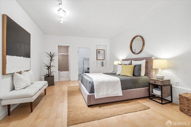 bedroom with wood-type flooring and ensuite bath