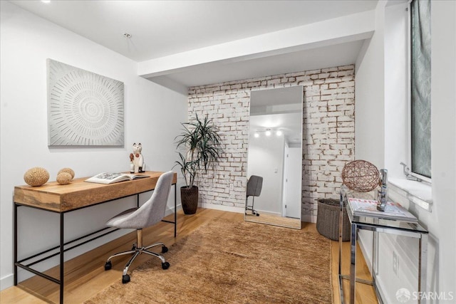 office with wood finished floors and brick wall