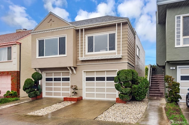 townhome / multi-family property with stucco siding, an attached garage, concrete driveway, and stairs