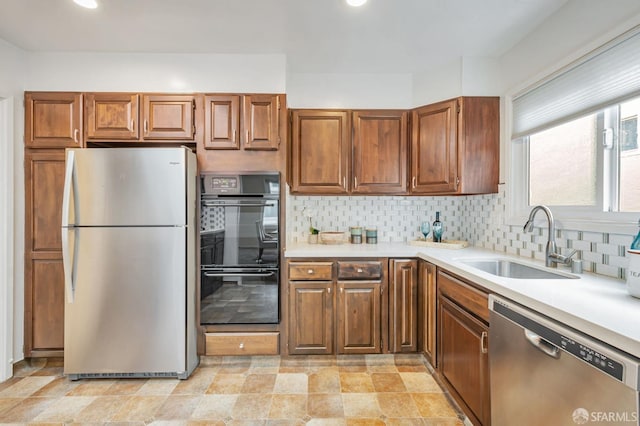 kitchen with a sink, stainless steel appliances, backsplash, and light countertops