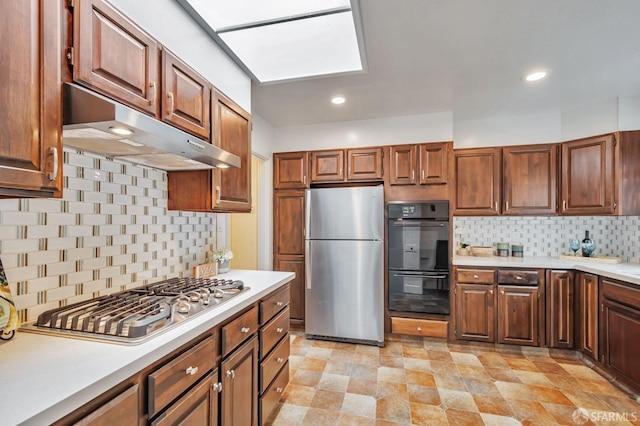 kitchen featuring under cabinet range hood, stainless steel appliances, backsplash, and light countertops