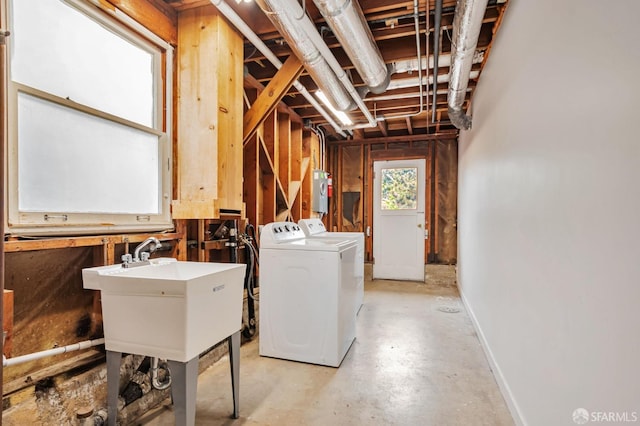 clothes washing area with washer and dryer, baseboards, laundry area, and a sink