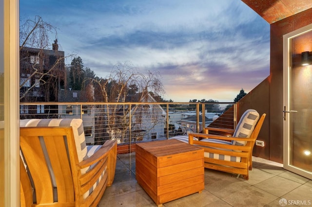 patio terrace at dusk featuring a balcony