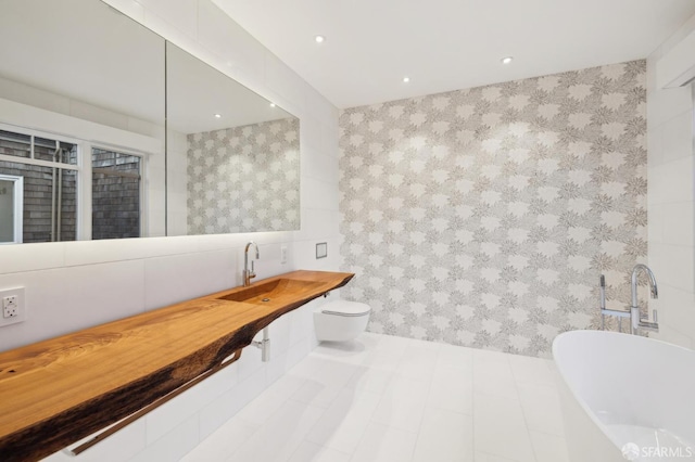 full bath featuring a freestanding tub, toilet, recessed lighting, a sink, and tile walls