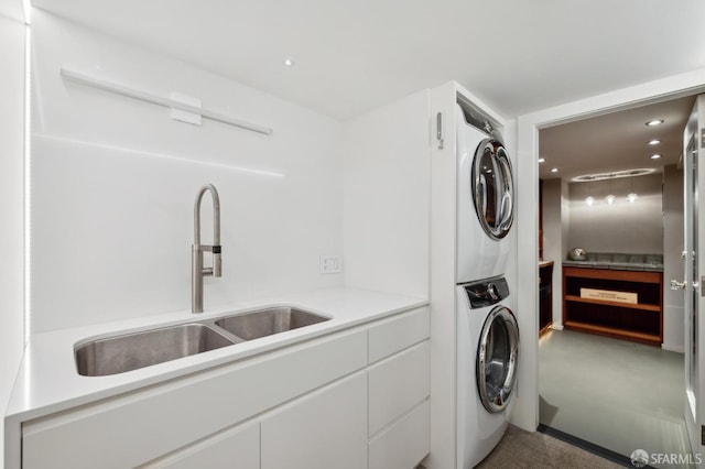 clothes washing area featuring laundry area, a sink, and stacked washing maching and dryer