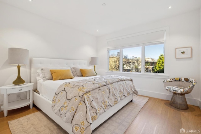 bedroom with baseboards, wood finished floors, and recessed lighting