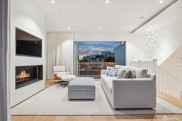 living room featuring recessed lighting, wood finished floors, and a glass covered fireplace