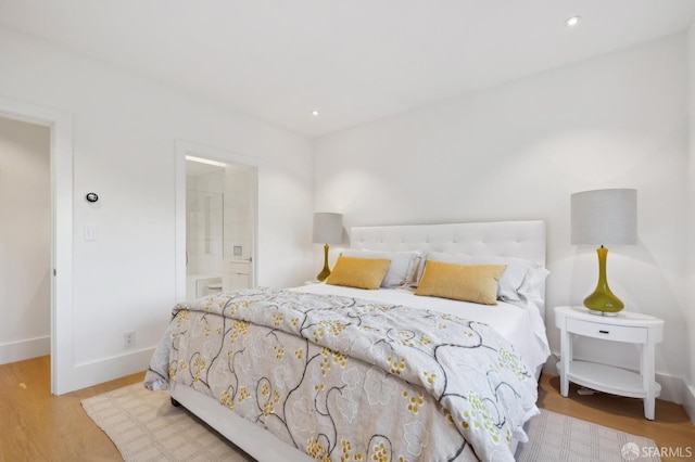 bedroom featuring baseboards, ensuite bathroom, wood finished floors, and recessed lighting