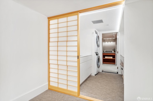 washroom featuring light carpet, laundry area, visible vents, and stacked washer / drying machine