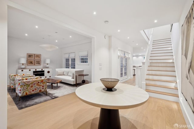 living area with ornamental molding, recessed lighting, wood finished floors, and stairs