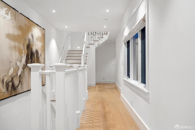 hall with recessed lighting, light wood-style flooring, baseboards, and stairs