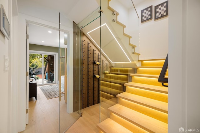 staircase with wood finished floors and recessed lighting