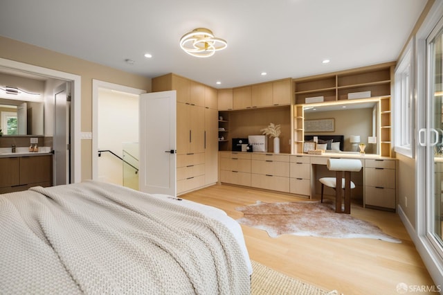 bedroom with light wood-type flooring, recessed lighting, and a sink