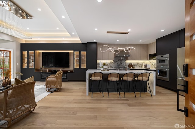 kitchen with modern cabinets, a breakfast bar, backsplash, light wood-type flooring, and recessed lighting