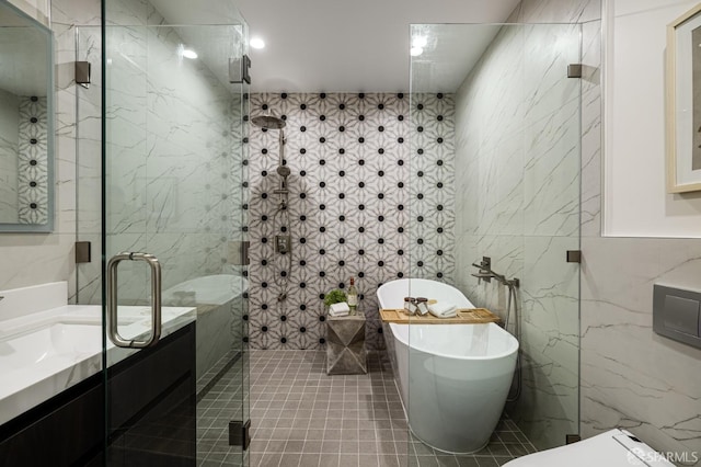 bathroom featuring tile walls, a stall shower, a freestanding bath, vanity, and tile patterned flooring