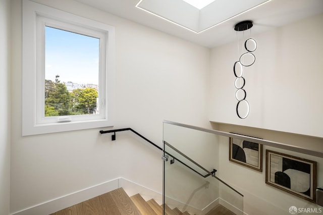 stairs with plenty of natural light, baseboards, and wood finished floors