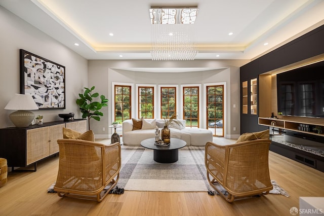 living room with a raised ceiling, wood finished floors, recessed lighting, baseboards, and a chandelier