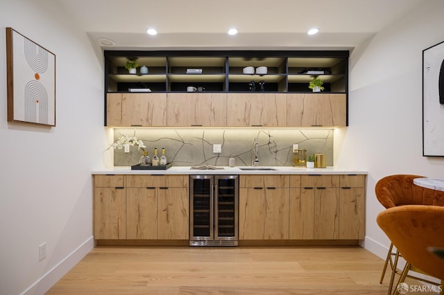 indoor wet bar featuring beverage cooler, light wood finished floors, tasteful backsplash, baseboards, and recessed lighting
