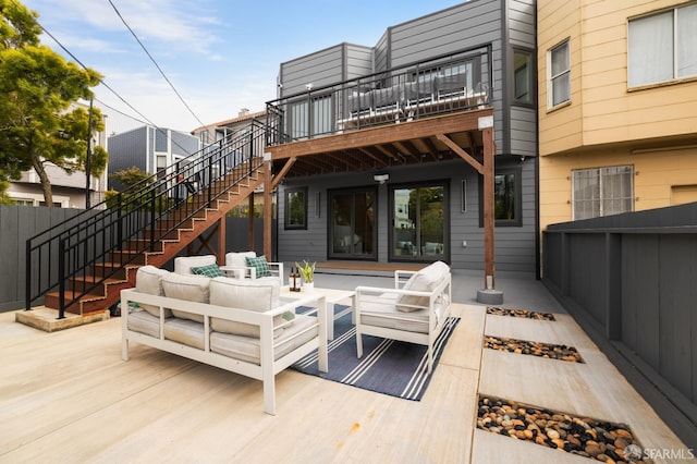 back of property with an outdoor living space with a fire pit, a balcony, stairway, a wooden deck, and fence