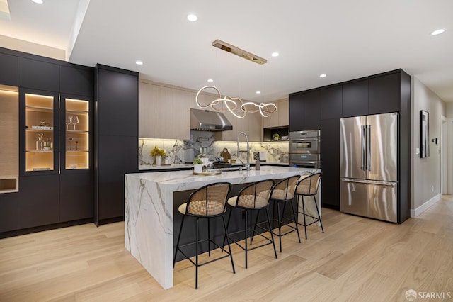 kitchen with stainless steel appliances, modern cabinets, under cabinet range hood, light wood finished floors, and recessed lighting