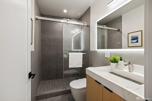 bathroom with toilet, a stall shower, and vanity