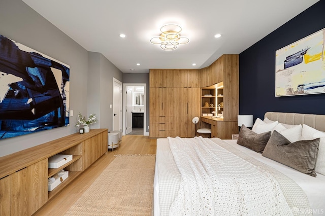 bedroom featuring light wood finished floors, recessed lighting, and ensuite bath